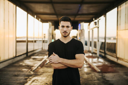 Young man standing with arms crossed at car wash tunnel - MIMFF00513