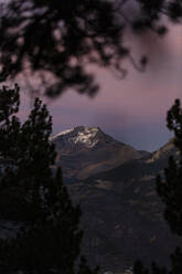 Spain, Huesca, Mountains reflecting in Ibon De Plan lake at purple sunset - OCAF00625