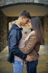 Smiling young couple embracing in town - ACPF01081