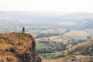 Weibliche Forscherin steht am Rande einer Bergklippe an einem sonnigen Tag - WPEF03962
