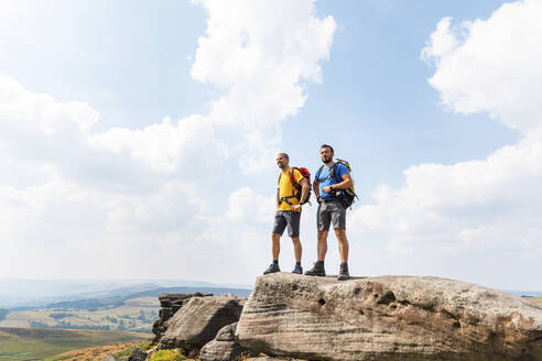 Männliche Entdecker mit Rucksack stehen am Rande eines Berges gegen den bewölkten Himmel - WPEF03968