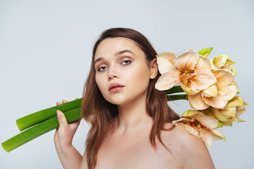 Shirtless woman with bunch of flowers staring while standing in studio - OIPF00157