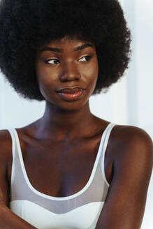 Beautiful Afro model in white bra looking away against wall - OIPF00200