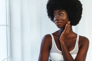 Smiling Afro young model looking away against white wall - OIPF00203