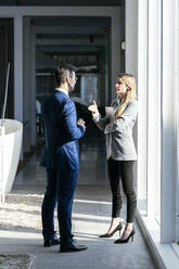 Geschäftsfrau streckt die Hand nach ihrem Partner aus, während sie im Büro steht - JSRF01291