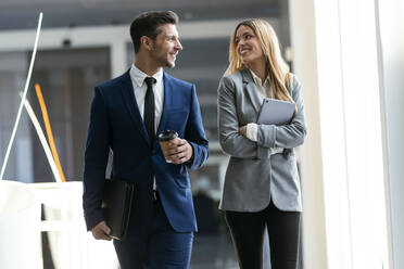 Colleague smiling while walking on office - JSRF01296