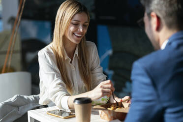 Businesswoman having lunch with colleague in cafeteria at office - JSRF01299