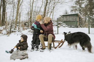 Mutter, die ihre Tochter füttert, während sie im Winter im Schnee ein Wochenende mit der Familie verbringt - DWF00567