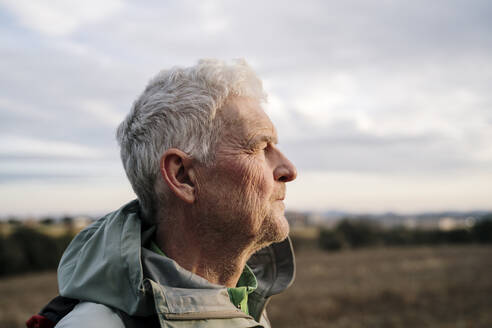 Älterer männlicher Wanderer schaut bei Sonnenuntergang weg - AFVF08101
