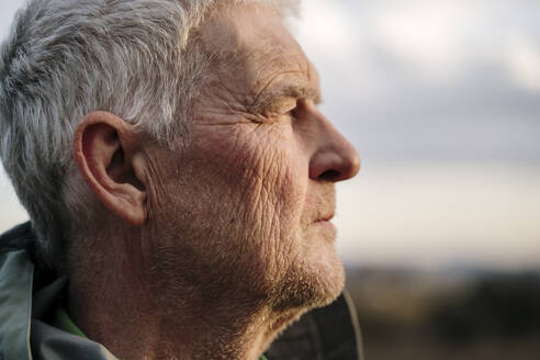 Senior man with wrinkled face against during sunset - AFVF08102