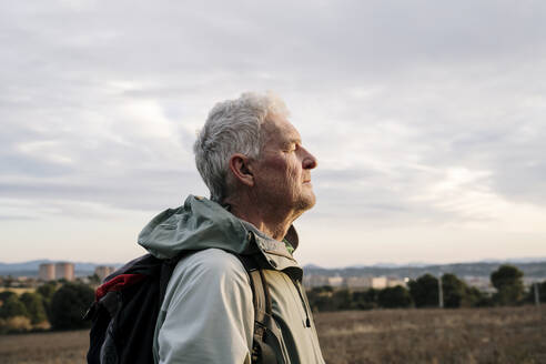 Senior male hiker with eyes closed at countryside during sunset - AFVF08105