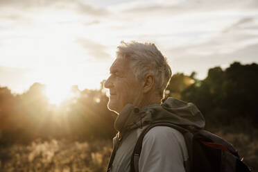 Senior man in warm clothing looking at sunset - AFVF08109