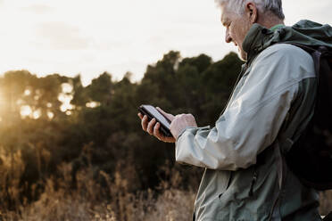 Älterer Mann benutzt sein Smartphone bei Sonnenuntergang - AFVF08120