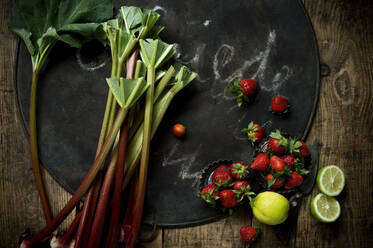 Frischer Rhabarber, Erdbeeren, Zitrone und Limette auf rustikalem Backblech - ASF06689