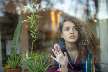 Thoughtful young woman seen through glass window at home - AXHF00131