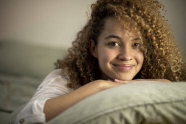 Lächelnde junge Frau auf dem Bett liegend zu Hause - AXHF00137