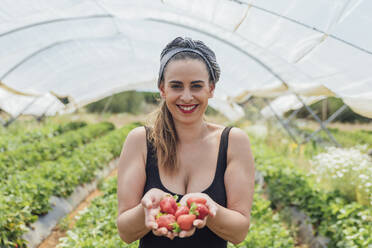 Glückliche schöne Bäuerin mit frischen Erdbeeren auf einem Bio-Bauernhof - JRVF00189