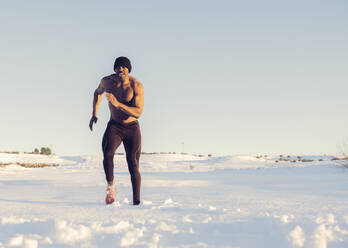 Sportler ohne Hemd beim Laufen im Schnee während des Sonnenuntergangs - JCCMF01022
