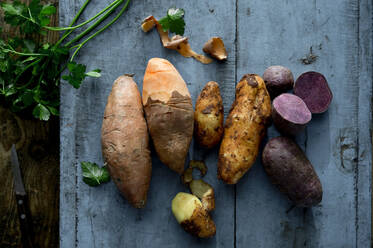 Parsley and different varieties of potatoes lying on wooden surface - ASF06710