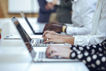 Geschäftskollegen beim Tippen mit dem Laptop am Schreibtisch im Coworking-Büro - JSRF01328