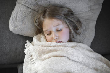 Krankes Mädchen schläft mit Decke auf Sofa zu Hause - KMKF01477