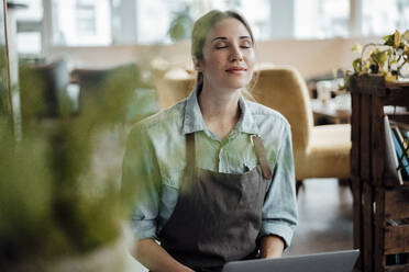 Weibliche Besitzerin sitzt mit Laptop im Cafe - JOSEF03086