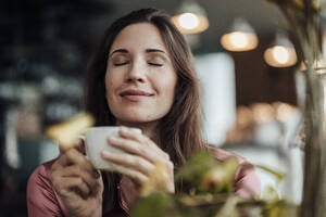 Smiling businesswoman smelling coffee in cafe - JOSEF03106