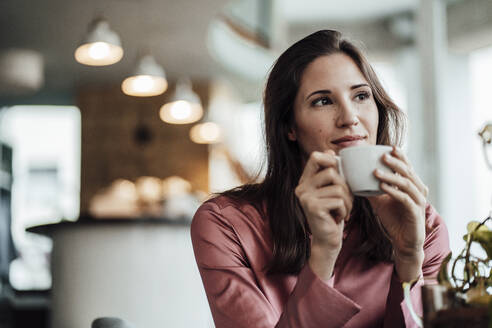 Businesswoman holding coffee cup while contemplating in cafe - JOSEF03109