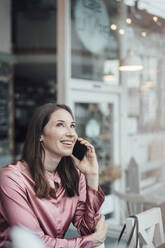 Lächelnde weibliche Fachkraft, die in einem Café mit einem Mobiltelefon spricht - JOSEF03111