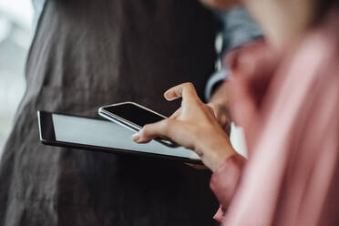 Geschäftsfrau, die in einem Café mit ihrem Mobiltelefon bezahlt - JOSEF03116