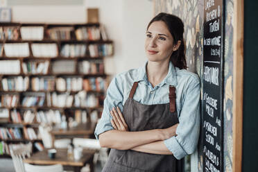 Nachdenkliche Unternehmerin mit verschränkten Armen, die im Café wegschaut - JOSEF03121