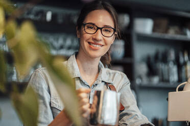 Lächelnde Managerin mit Kaffeekanne in einem Cafe - JOSEF03135
