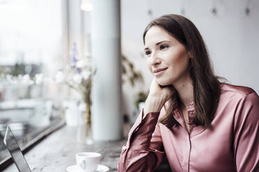 Female entrepreneur looking away with hand on chin at cafe - JOSEF03146