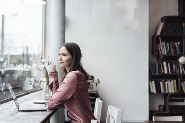 Businesswoman having coffee at table while sitting in cafe - JOSEF03147