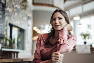 Lächelnde Geschäftsfrau, die in einem Café sitzt und nachdenkt - JOSEF03177