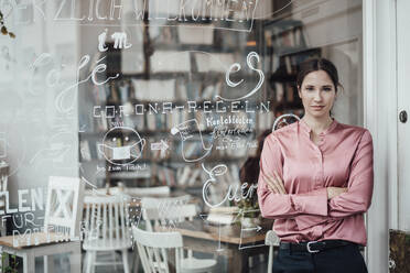 Confident female entrepreneur with arms crossed outside coffee shop - JOSEF03183