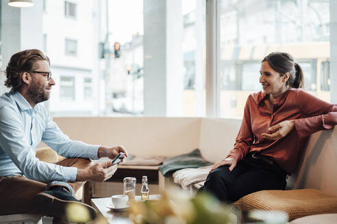 Männlicher Unternehmer im Gespräch mit einer Kollegin in einem Café - JOSEF03185