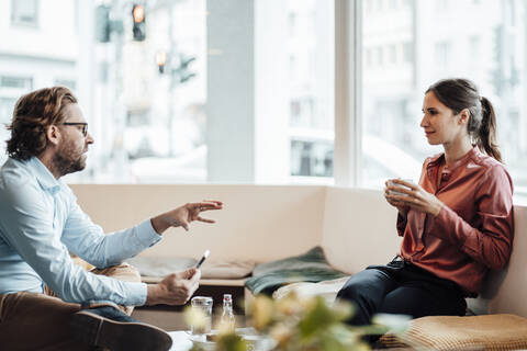 Female entrepreneur having coffee while discussing with male colleague at coffee shop stock photo