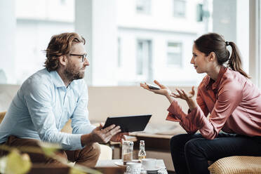 Businesswoman explaining male colleague while discussing during meeting at cafe - JOSEF03192