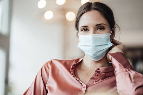 Female entrepreneur with protective face mask at coffee shop - JOSEF03203