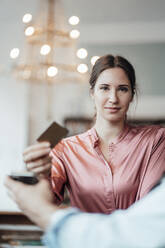 Selbstbewusste Geschäftsfrau, die mit Kreditkarte an den männlichen Besitzer eines Cafés zahlt - JOSEF03214