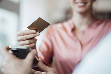 Weibliche Kundenhand, die mit Kreditkarte an den männlichen Besitzer eines Cafés zahlt - JOSEF03215