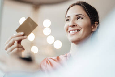 Weibliche Fachkraft schaut weg, während sie in einem Café mit Kreditkarte bezahlt - JOSEF03218