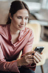 Female entrepreneur using mobile phone at coffee shop - JOSEF03224