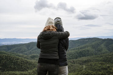 Paar umarmt, während Blick auf Berge gegen den Himmel im Winter - AFVF08125