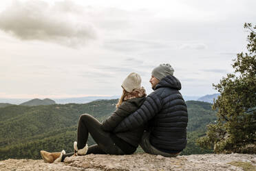 Couple looking at mountains against sky while sitting on observation point - AFVF08133