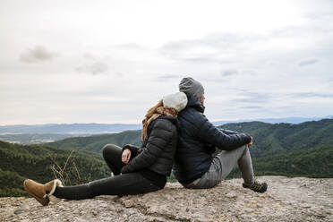 Couple sitting back to back on observation point against sky - AFVF08137
