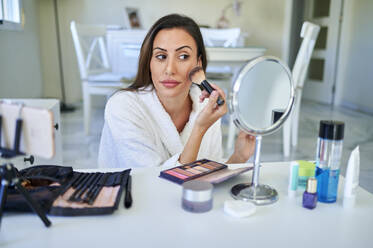 Female influencer applying make-up while vlogging on smart phone at home - KIJF03521