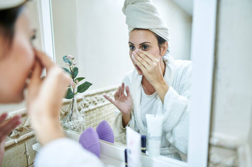 Frau beim Abschminken vor dem Badezimmerspiegel - KIJF03545