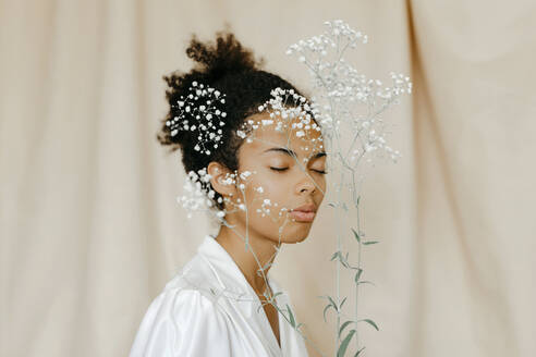 Weiße Blumen vor dem Gesicht einer jungen Frau - TCEF01512